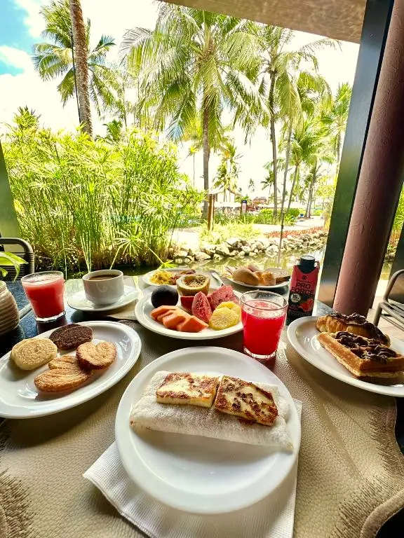 Mesa de café da manhã ao ar livre com frutas, waffles, sucos e café