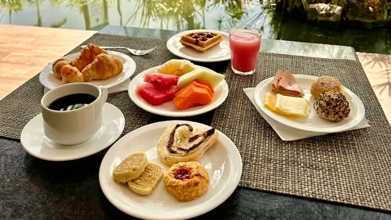 Café da manhã com croissants, frutas, pães doces e uma xícara de café