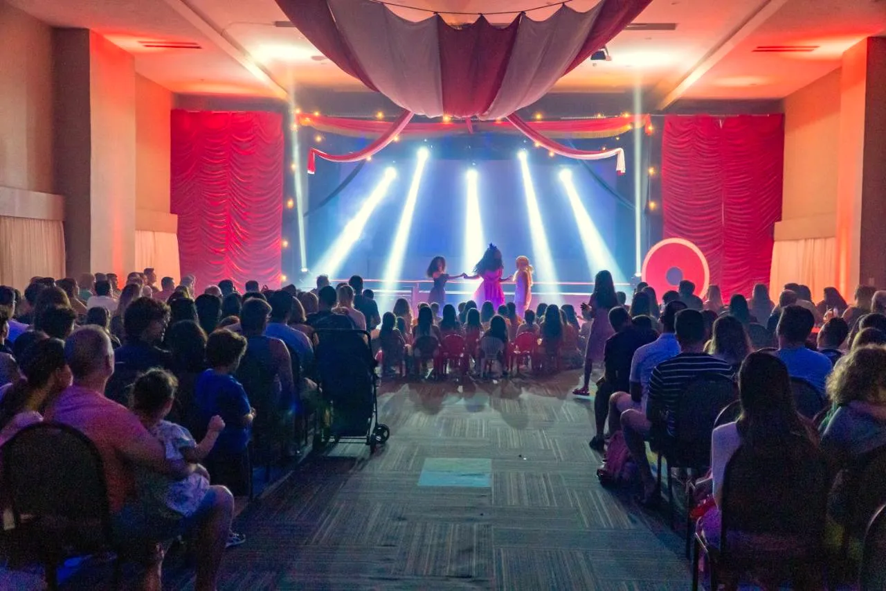 Plateia diante do palco iluminado durante um espetáculo noturno
